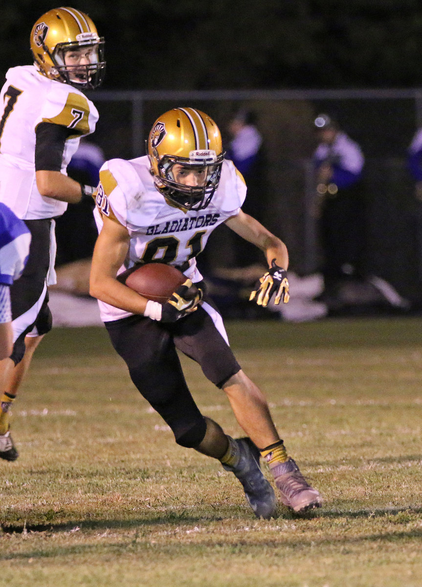 Image: Gladiator quarterback Ryan Connor(7) hands off to fullback Dylan McCasland(81) who hits into the middle of the Blooming Grove defensive line.