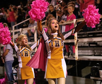 Image: Cheerleaders Halee Turner and Karson Holley sport pink pom-poms and pink capes while inspiring the fans and ball players.