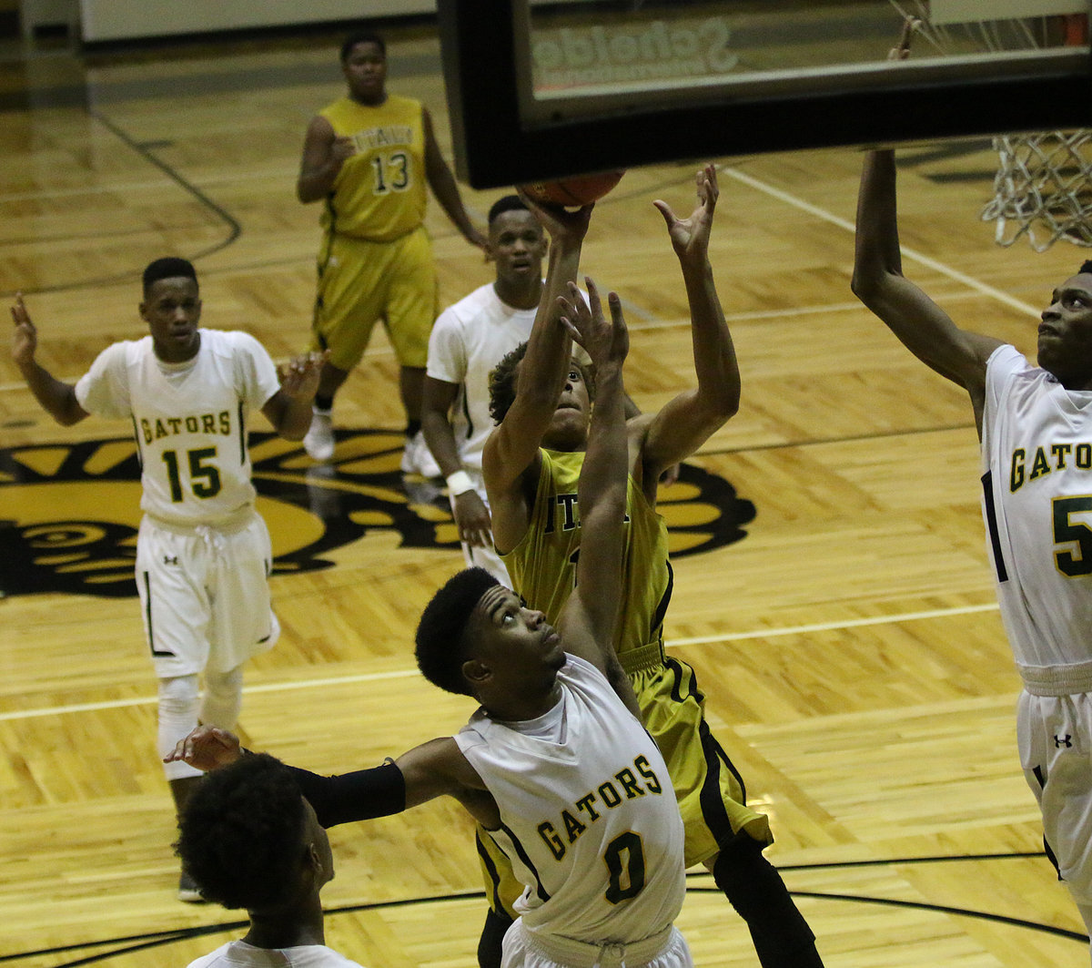 Image: Italy’s Keith Davis, Jr. (11) attacks the basket with Gator defenders trying to chomp down on him.