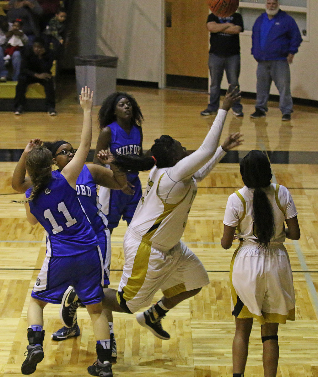 Image: Senior Lady Gladiator Shercorya Chance(33) displays her athleticism to score the basket after splitting a pair of Milford defenders.