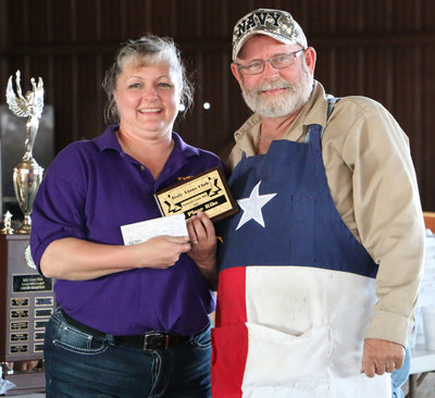 Image: Italy Lions Club member Flossie Gowin presents Terry Bowling, of Blooming Grove, with his 1st Place Ribs plaque and his $210.00 winner’s check. Mr. Bowling was also the cook-off’s Grand Champion, was awarded 3rd Place in the Chicken category, received 4th Place in the Brisket category, and received 6th Place in the Pork Butt category. He dedicated his accomplishments to his wife of 19 years, Glenda Ann Bowling (1953 – 2016), who passed away just two weeks before the cook-off.