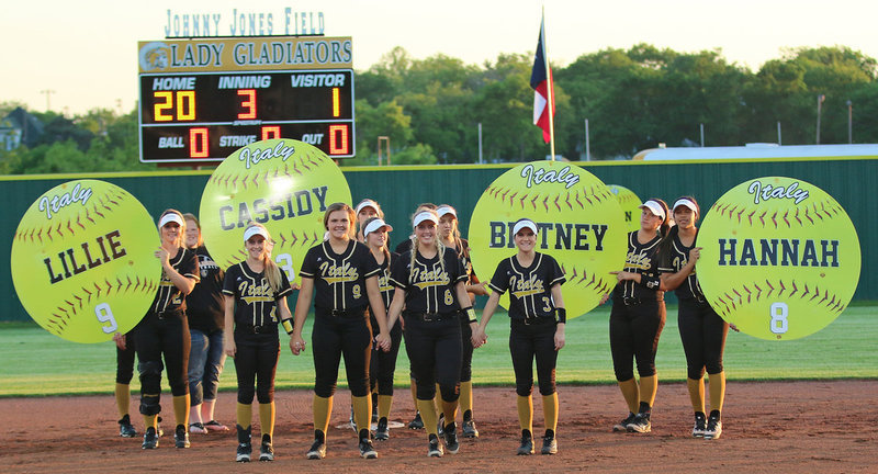 Image: Senior Italy Lady Gladiators Britney Chambers(4), Lillie Perry(9), Hannah Washington(8) and Cassidy Childers(3) are joined by their teammates during their Senior Walk at Johnny Jones Field.