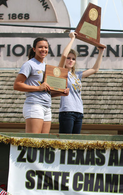 Image: Lady Gladiators April Lusk and Halee Turner  hold up their reminders of their team’s journey to becoming state champions during the parade for all to see.