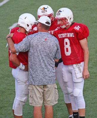 Image: Red squad’s Clayton Miller(8) gets coached up along with a couple of teammates during a critical drive late in the second-quarter.