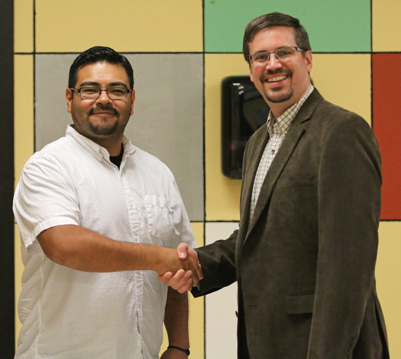 Image: The outgoing Italy High School band director, Jesus Perez, passes the conductor’s baton over to the incoming band director, Jonathan VanOmmeren, during a farewell/welcome event held to honor both men inside the school’s cafeteria.
