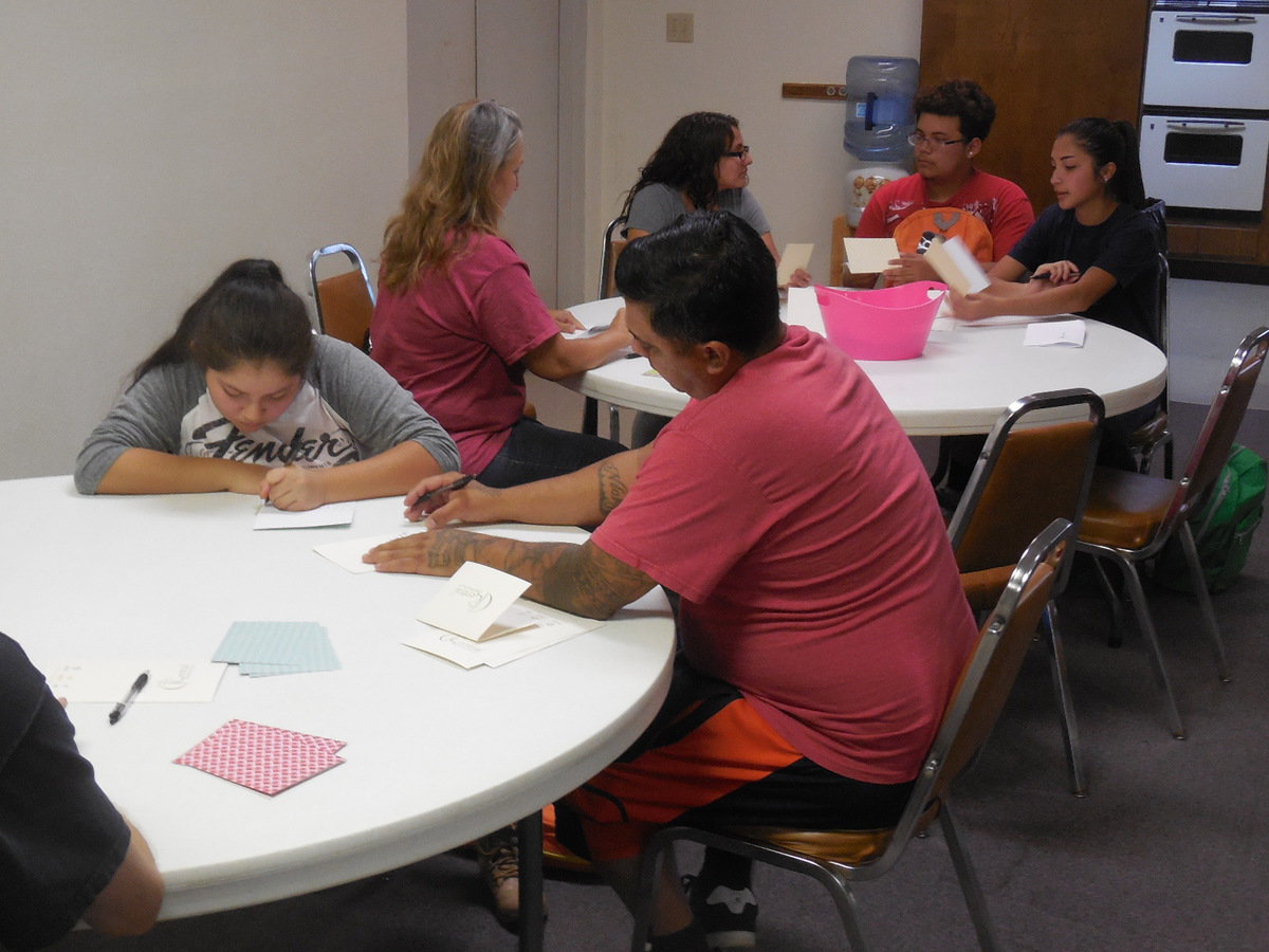 Image: CBC members write notes to place in the backpacks.