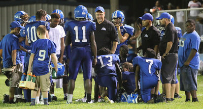 Image: Milford head coach Ronny Crumpton and his staff huddle with their players with the game still in doubt.