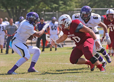 Image: Austin College junior nose guard Zain Byers (#50 in Crimson) rips his way into the Whittier Poets backfield.