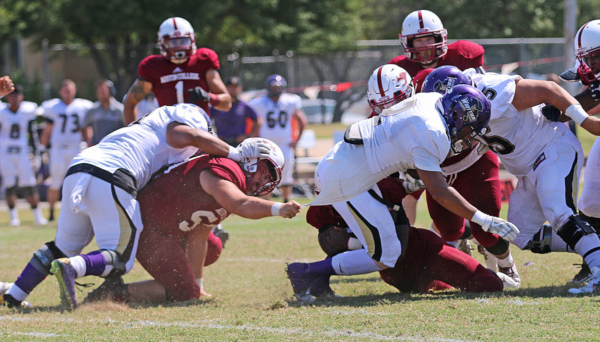 Image: Austin College junior nose guard Zain Byers (#50 in Crimson) hangs on by the jersey until help arrives to bring down a Whittier Poet running back.