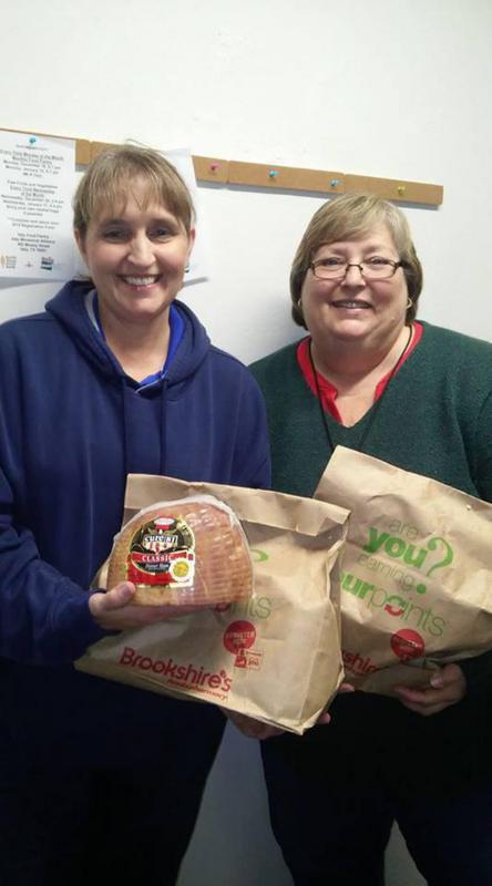 Image: Tessie, Manager of Spring Market presents 45 hams to Susan Wooten, Food Pantry Director. Local patrons also donated bags of groceries to the pantry.